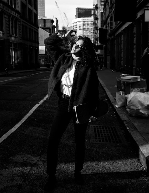 A Miami creative on the street holding a skateboard, in black and white